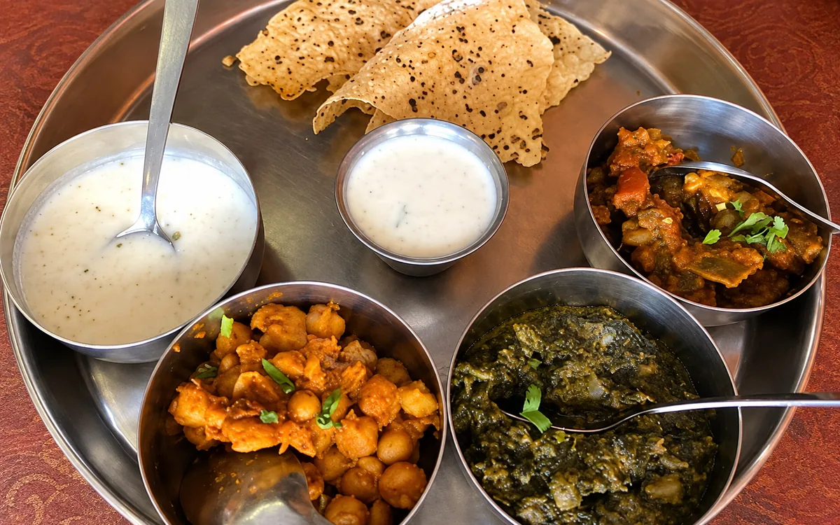 Tandoor thali with vegetable dishes, raita, and papadum — AI-retouched restaurant photo